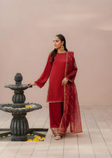 Khizra Artstyle cherry-red embroidered 3-piece suit — Gul Naaz design, full front view beside a stone fountain, looking to the side