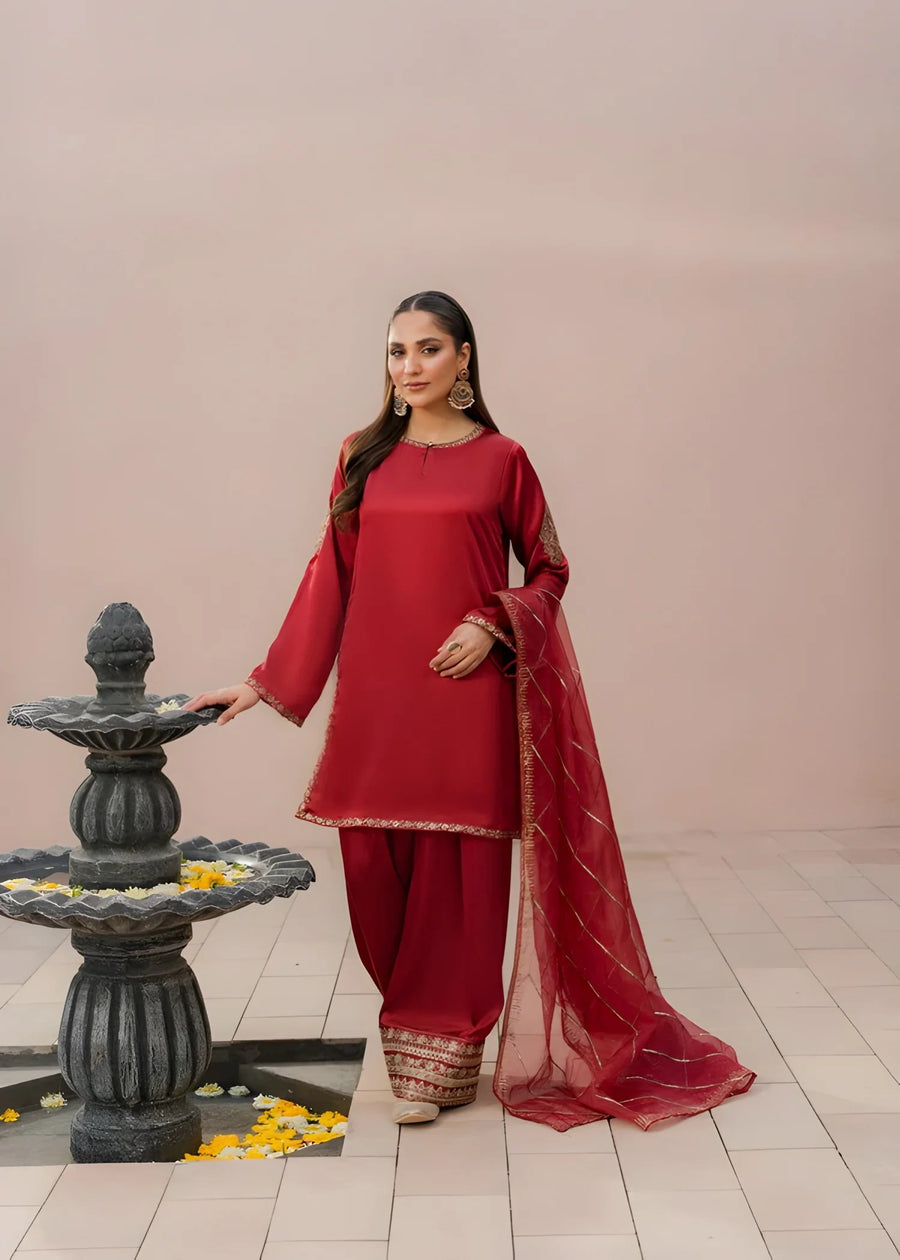 Khizra Artstyle cherry-red embroidered 3-piece suit — Gul Naaz design, full front portrait beside a stone fountain